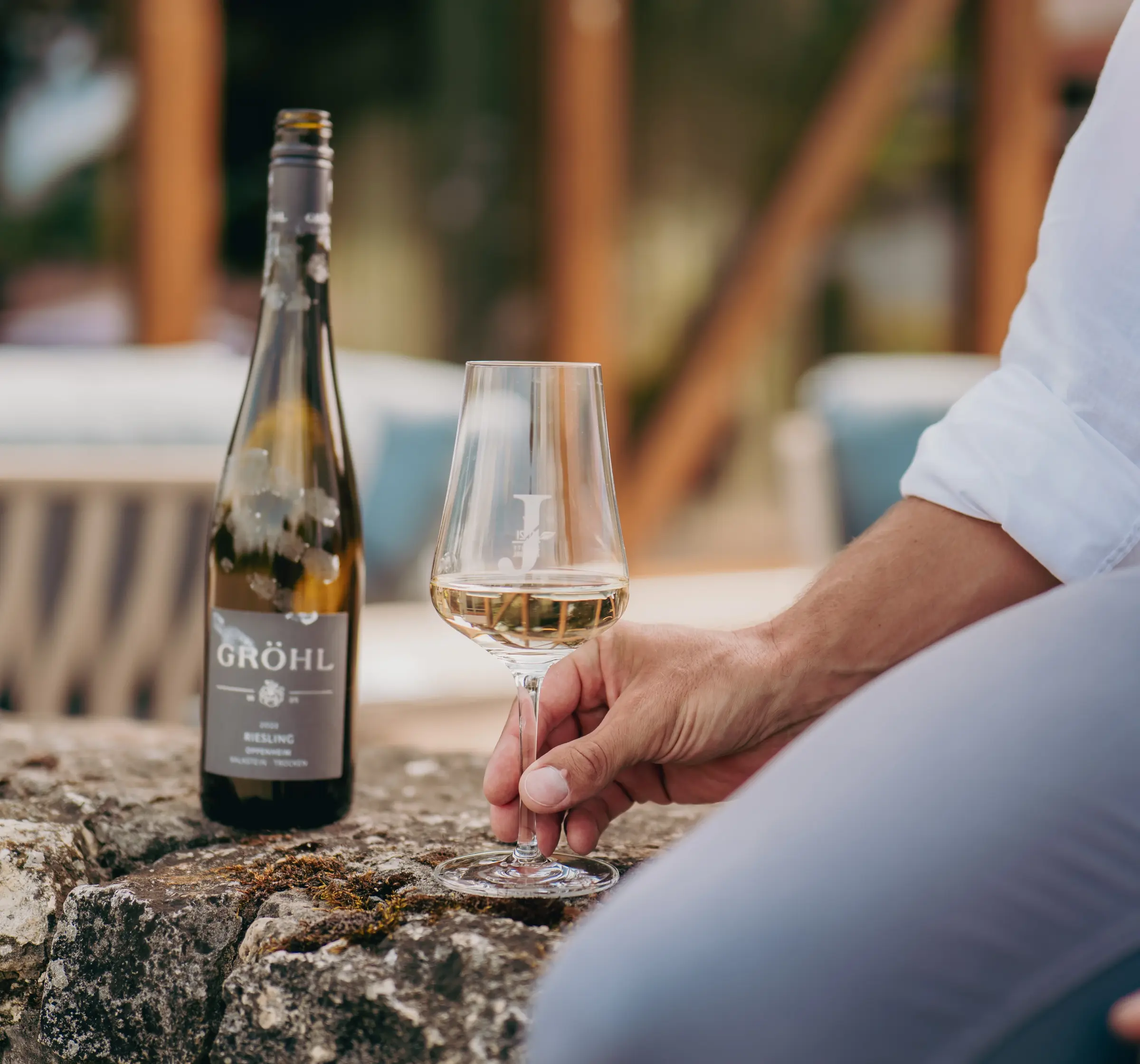 Mann sitzt auf Mauer mit einem Glas Wein von Jordan's Untermühle