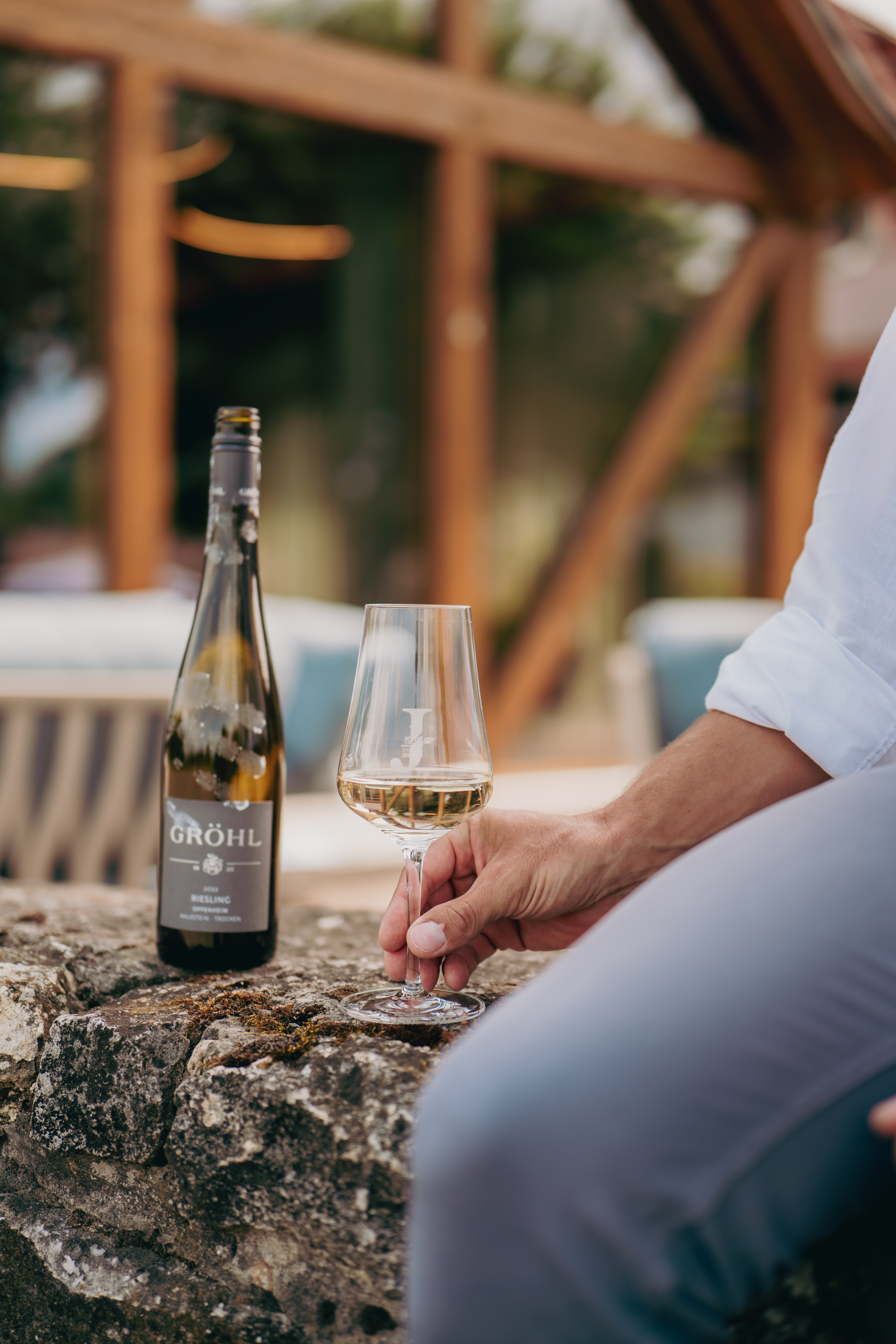 Mann sitzt auf Mauer mit einem Glas Wein von Jordan's Untermühle